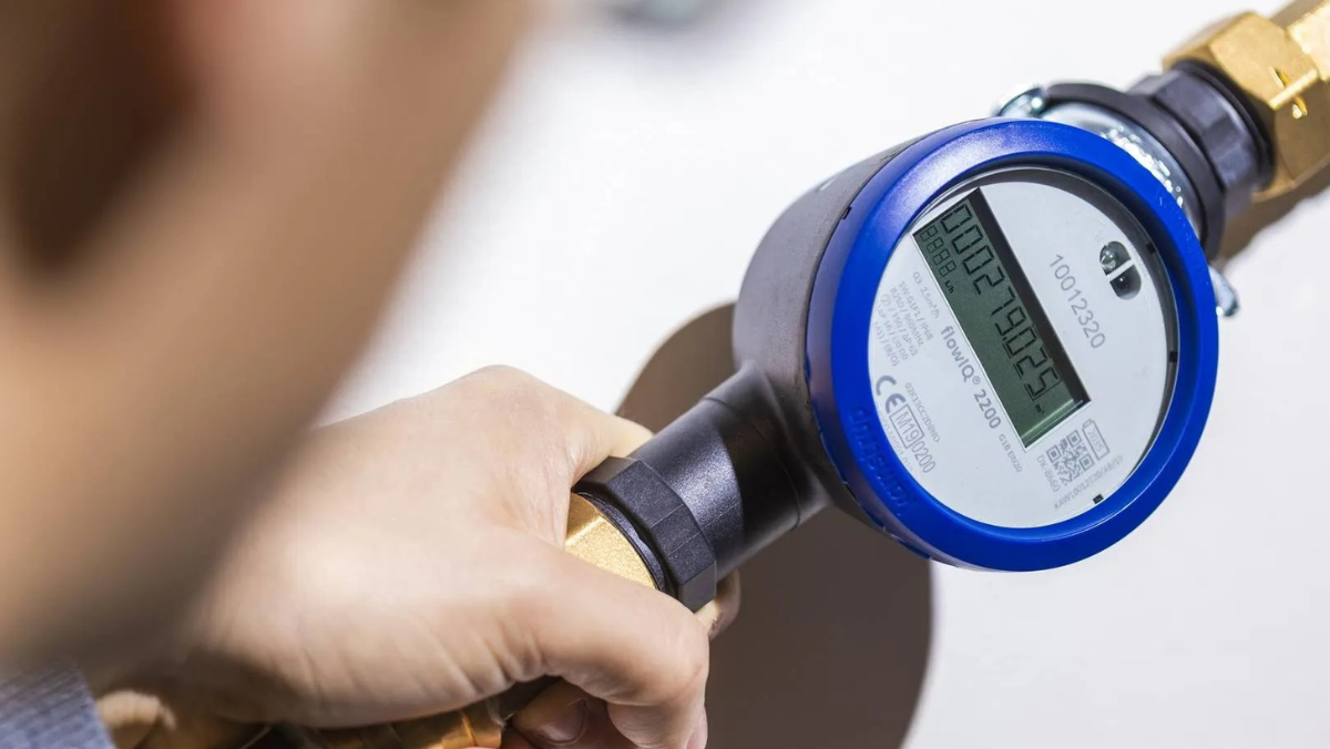 Hand adjusting a digital water meter with a clear display reading
