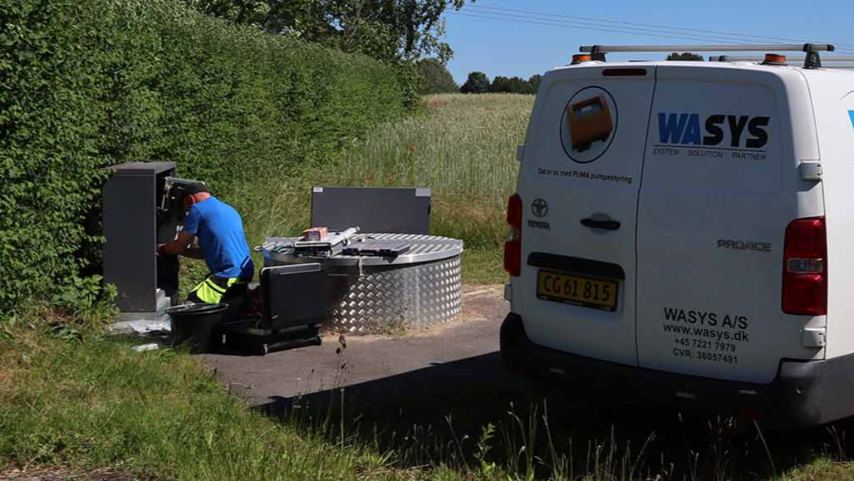 Technician servicing water control equipment beside WASYS service van in rural field