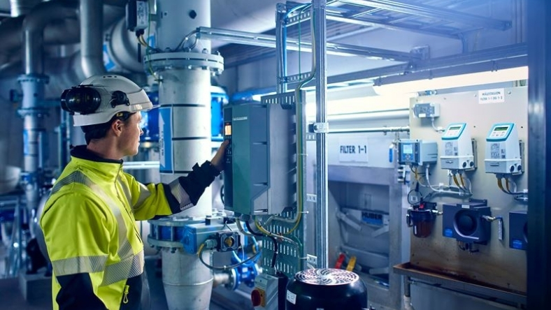 Technician monitoring industrial control panels inside a water treatment facility
